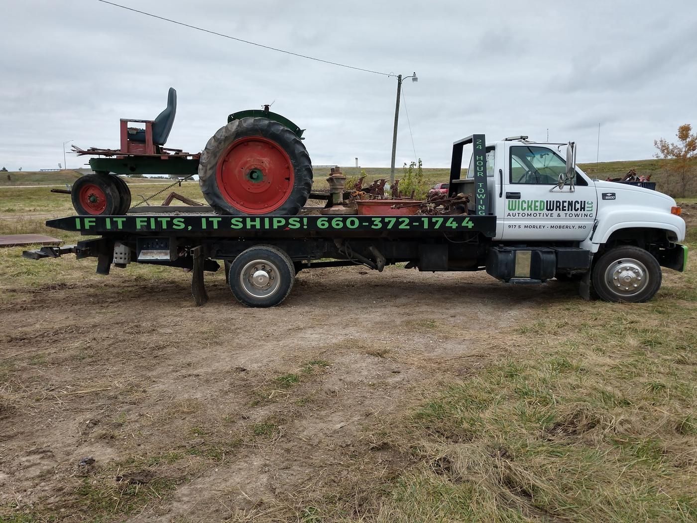 Side of the Wicked Wrench flatbed lettered If It Fits, It Ships with a vintage tractor loaded