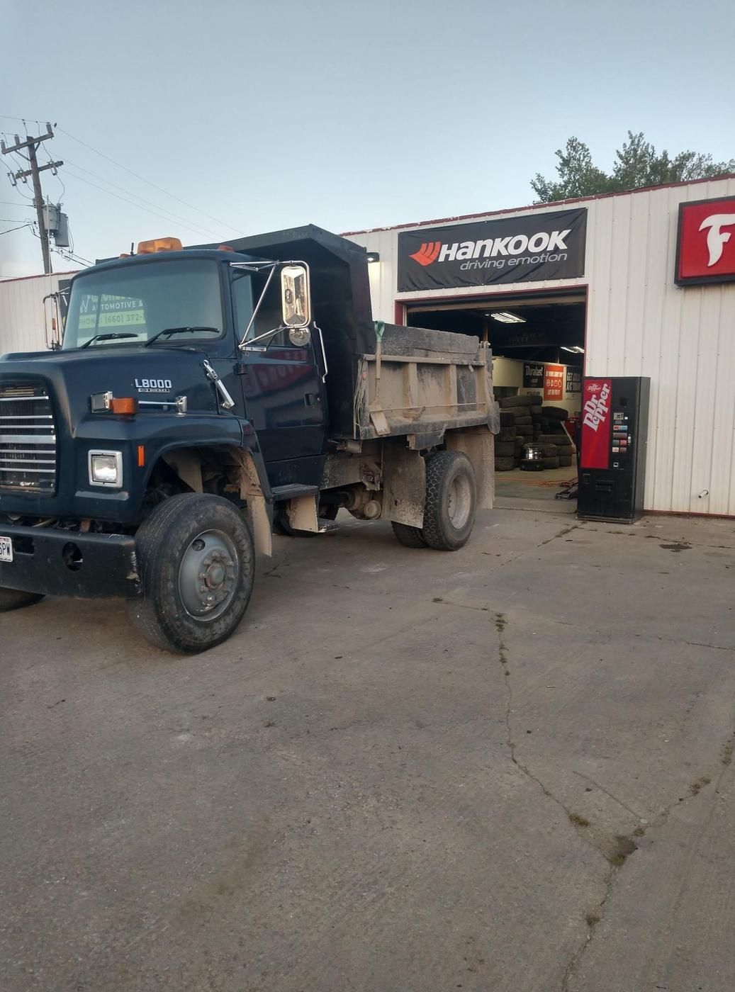 Dump truck parked at the open service bay under the Hankook banner