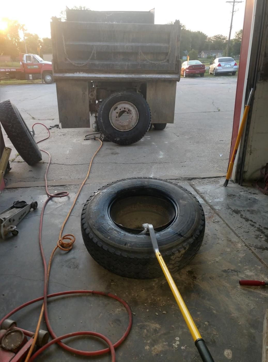 Truck tire being changed at the bay door with a wrecker in the background